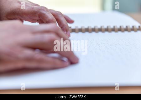 Blinde oder sehbehinderte Person, die ein Buch liest, das mit brailleschrift gedruckt ist. Stockfoto