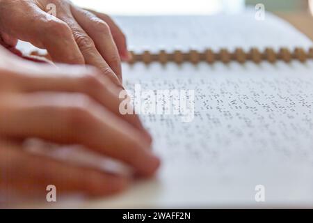 Blinde oder sehbehinderte Person, die ein Buch liest, das mit brailleschrift gedruckt ist. Stockfoto