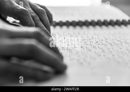 Blinde oder sehbehinderte Person, die ein Buch liest, das mit brailleschrift gedruckt ist. Stockfoto
