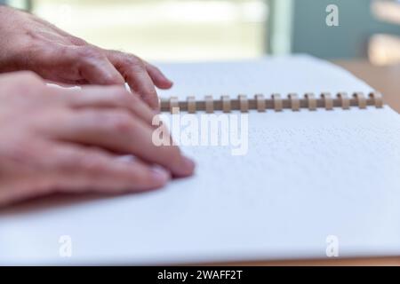 Blinde oder sehbehinderte Person, die ein Buch liest, das mit brailleschrift gedruckt ist. Stockfoto