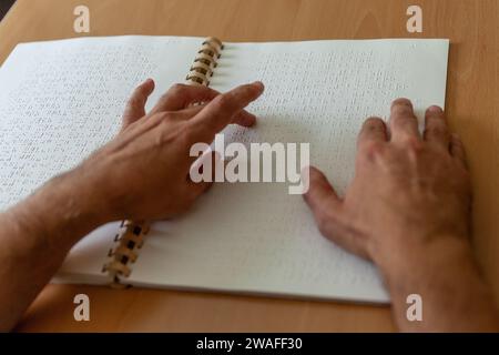 Blinde oder sehbehinderte Person, die ein Buch liest, das mit brailleschrift gedruckt ist. Stockfoto