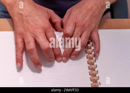 Blinde oder sehbehinderte Person, die ein Buch liest, das mit brailleschrift gedruckt ist. Stockfoto