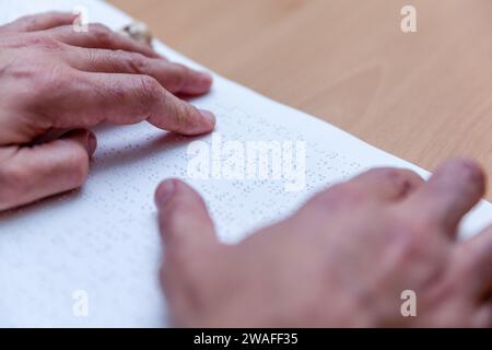 Blinde oder sehbehinderte Person, die ein Buch liest, das mit brailleschrift gedruckt ist. Stockfoto