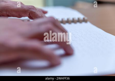 Blinde oder sehbehinderte Person, die ein Buch liest, das mit brailleschrift gedruckt ist. Stockfoto