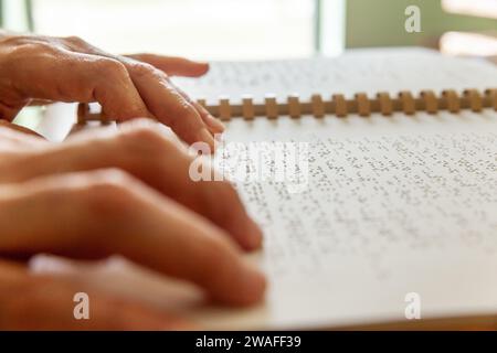 Blinde oder sehbehinderte Person, die ein Buch liest, das mit brailleschrift gedruckt ist. Stockfoto