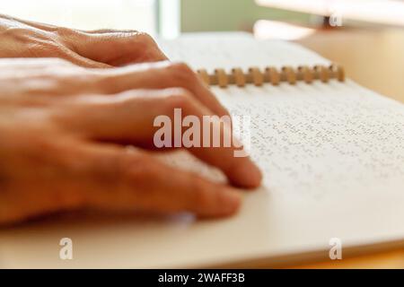Blinde oder sehbehinderte Person, die ein Buch liest, das mit brailleschrift gedruckt ist. Stockfoto