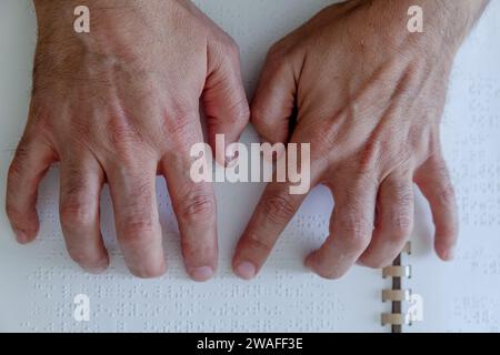 Blinde oder sehbehinderte Person, die ein Buch liest, das mit brailleschrift gedruckt ist. Stockfoto