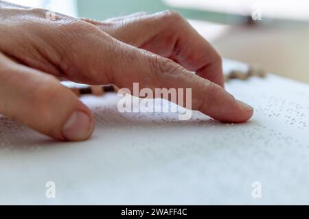 Blinde oder sehbehinderte Person, die ein Buch liest, das mit brailleschrift gedruckt ist. Stockfoto