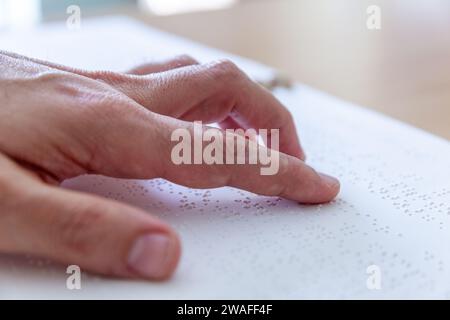 Blinde oder sehbehinderte Person, die ein Buch liest, das mit brailleschrift gedruckt ist. Stockfoto