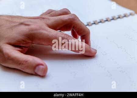 Blinde oder sehbehinderte Person, die ein Buch liest, das mit brailleschrift gedruckt ist. Stockfoto