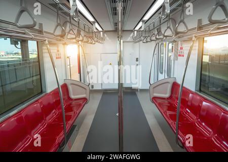Innenraum eines Personenkraftwagens eines Pendlerzuges. Rote Kunststoffsitze und Chrom-Handläufe in einem elektrischen Zugwagen. Stockfoto