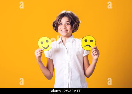 Mädchen hält traurige und glückliche Emoticons in Händen. Psychische Gesundheit, Psychologie und kindliches Gefühlskonzept Stockfoto