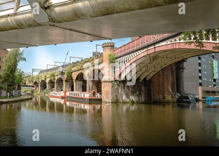 Der beschauliche Manchester Bridgwater Canal, flankiert von einer historischen Brücke mit mehreren Bögen. Urbaner Charme in ruhiger Lage am Wasser. Reisetourismuskonzept Stockfoto