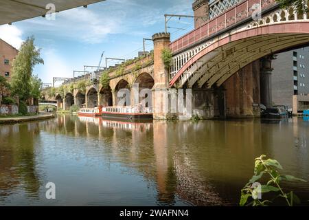 Der beschauliche Manchester Bridgwater Canal, flankiert von einer historischen Brücke mit mehreren Bögen. Urbaner Charme in ruhiger Lage am Wasser. Reisetourismuskonzept Stockfoto