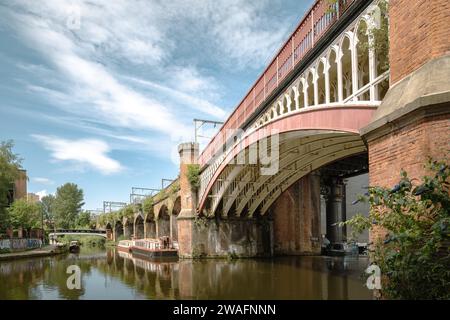 Der beschauliche Manchester Bridgwater Canal, flankiert von einer historischen Brücke mit mehreren Bögen. Urbaner Charme in ruhiger Lage am Wasser. Reisetourismuskonzept Stockfoto