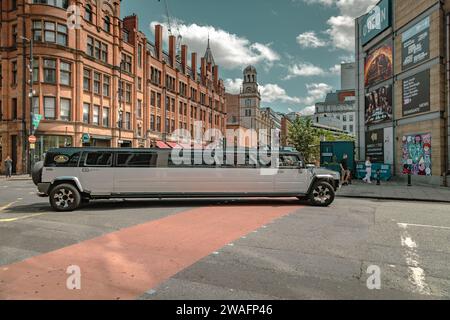 Eine Stretchlimousine von Hummer, die an einer Straßenkreuzung im Stadtzentrum abbiegt. Fahren, Party, Nachtleben, Luxusreisen, Prominente-Konzept Stockfoto