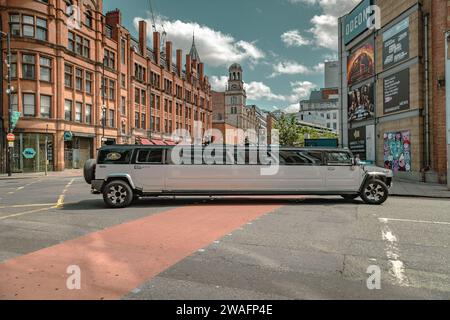 Eine Stretchlimousine von Hummer, die an einer Straßenkreuzung im Stadtzentrum abbiegt. Fahren, Party, Nachtleben, Luxusreisen, Prominente-Konzept Stockfoto