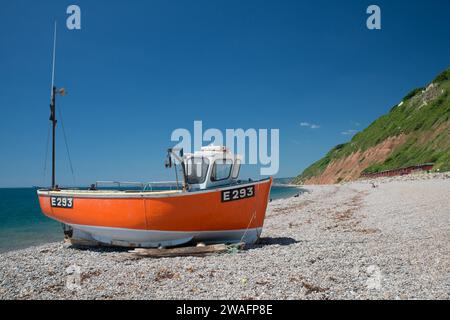 Oranges Fischerboot auf dem Schindel von Branscombe Mouth Beach, Devon, England Stockfoto