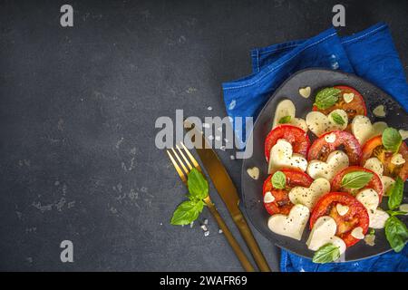 Caprese Salat zum Valentinstag Abendessen, mit Tomaten, Käse in Form von Herzen, Basilikum. Valentine day Menü Konzept Draufsicht Kopieplatz Stockfoto