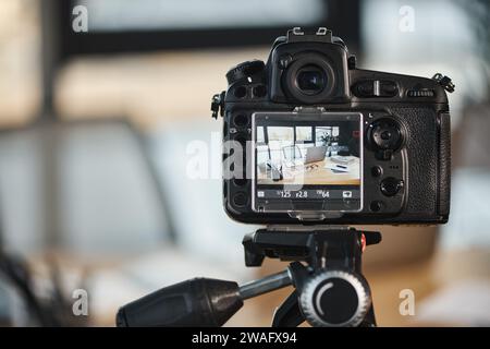 Nahaufnahme der Digitalkamera mit Schreibtisch auf dem Bildschirm im unscharfen Büro, Erstellung von Videoinhalten Stockfoto