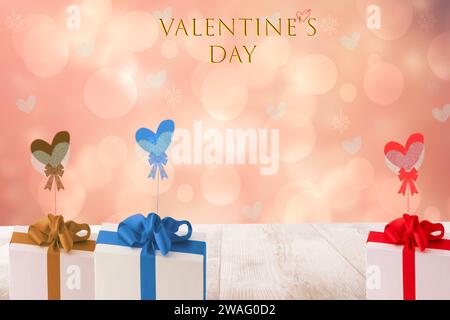 Happy Valentinstag Illustration mit mehreren farbigen Geschenkboxen mit Bändern und Bögen auf einem hellen Holztisch über verschwommenem Herzen Hintergrund. Karte Stockfoto