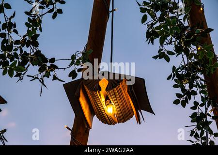 Bücher mit Glühbirnen und Ornamenten auf Holzpfosten mit dem Himmel im Hintergrund Stockfoto