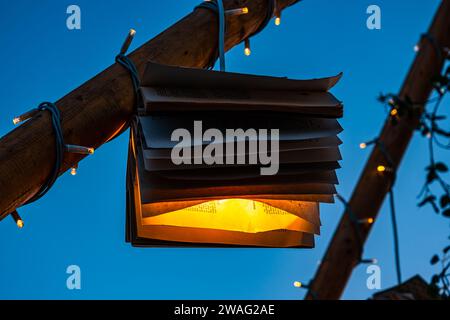 Bücher mit Glühbirnen und Ornamenten auf Holzpfosten mit dem Himmel im Hintergrund Stockfoto