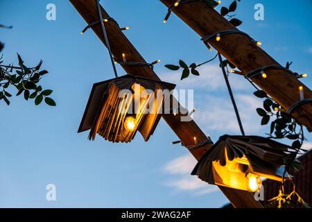 Bücher mit Glühbirnen und Ornamenten auf Holzpfosten mit dem Himmel im Hintergrund Stockfoto