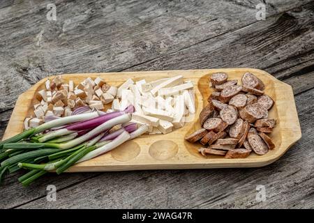 Traditionelle rumänische Küche auf hölzernem Plateau mit Zwiebeln, Käse, Schinken und Würstchen auf einem alten Holztisch Stockfoto