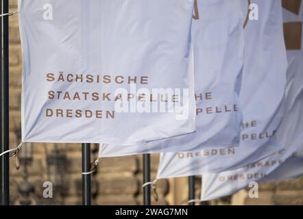 Dresden, Deutschland. Januar 2024. Fahnen mit der Aufschrift „Sächsische Staatskapelle Dresden“ winken im Wind vor der Semperoper. Robert Michael/dpa/Alamy Live News Stockfoto