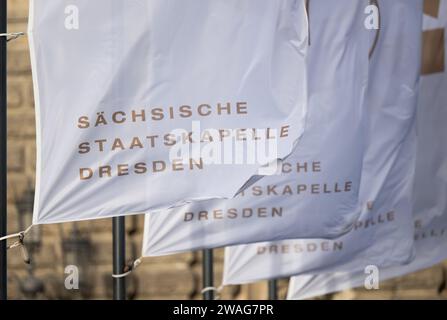 Dresden, Deutschland. Januar 2024. Fahnen mit der Aufschrift „Sächsische Staatskapelle Dresden“ winken im Wind vor der Semperoper. Robert Michael/dpa/Alamy Live News Stockfoto