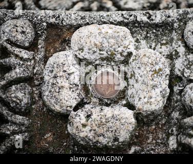 Eine Nahaufnahme einer antiken Münze auf einem Bett aus schneebedeckten grauen Felsen Stockfoto