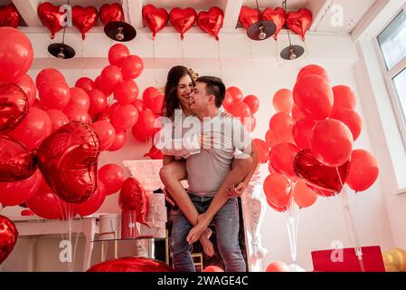 Ein Paar, das herumspielt, lacht, sich gegenseitig in die Augen sieht. Frau sitzt auf dem Rücken des Mannes. Lifestyle-Urlaub Valentinstag. Verspielter, romantischer Moment Stockfoto