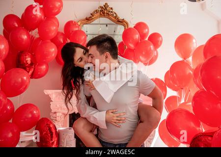 Ein Paar, das herumspielt, lacht, sich gegenseitig in die Augen sieht. Frau sitzt auf dem Rücken des Mannes. Lifestyle-Urlaub Valentinstag. Verspielter, romantischer Moment Stockfoto