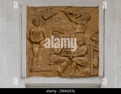 Ein Basrelief auf einem Gebäude der Schule N56, das sowjetische Schüler zeigt, die Geräte Almaty Kasachstan bauen. Künstler Ivan Vakhek. 1936 Stockfoto