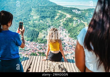 Rückansicht mit einem nicht identifizierbaren blonden jungen Mädchen, das den Blick vom belvedere Point auf dem Berg Tampa über Brasov, Rumänien, genießt. Stockfoto