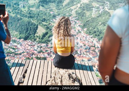 Rückansicht mit einem nicht identifizierbaren blonden jungen Mädchen, das den Blick vom belvedere Point auf dem Berg Tampa über Brasov, Rumänien, genießt. Stockfoto