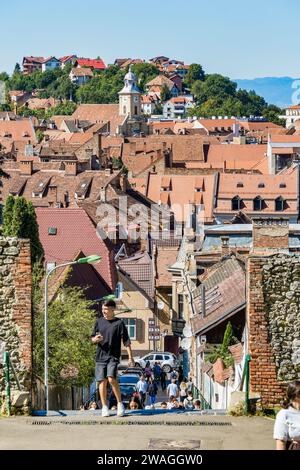 Touristen auf den Straßen der Altstadt von Brasov. Mittelalterliche alte Häuser mit roten Ziegeldächern Stockfoto