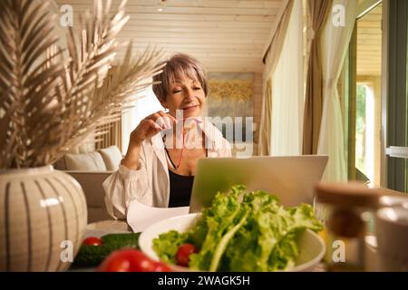 Eine alte Dame mit Fliederhaaren arbeitet fernab in ihrer Küche Stockfoto