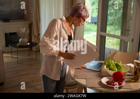 Ältere Dame zu Hause in der Küche mit Laptop Stockfoto