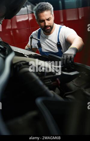 Konzentrierter Kfz-Servicetechniker, der den Kühler überprüft Stockfoto