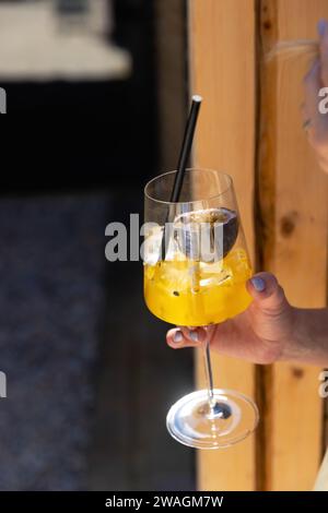 Mädchen trinkt Spritz aperol. Frau, die Glas mit orangefarbenem Cocktail hält. Abendliche Entspannung in der Bar oder im Restaurant. Stockfoto