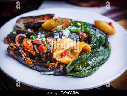 Eingelegter gebratener Aubergine und grüner Paprika, gefüllt mit Knoblauch, Chili, rotem Pfeffer, Essig, Zitrone, Koriander, Petersilie, Gehackte Tomaten und Gewürze, Stockfoto