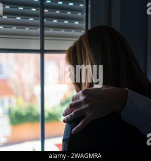 Die Hand eines Mannes auf der Schulter einer Frau, die an Depressionen und Traurigkeit leidet. Stockfoto