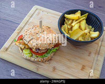 Saftiger Fischburger mit Kartoffelchips auf Holzbrett Stockfoto