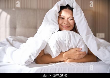 Fröhliche Frau, die nach dem Aufwachen Zeit in einem gemütlichen Schlafzimmer verbringt Stockfoto