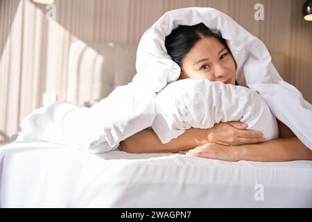 Verschlafene Dame, die nach dem Aufwachen in einem komfortablen Schlafzimmer Zeit verbringt Stockfoto