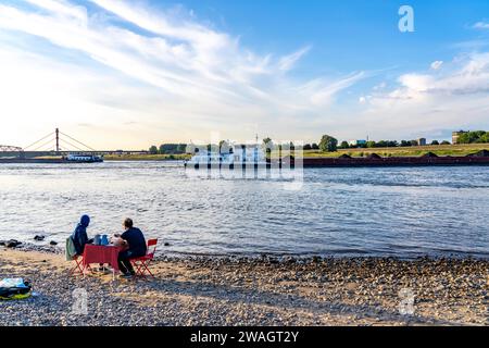 Der Rhein bei Duisburg-Bärl, Mann und Frau beim Picknick am Rheinstrand, bei Ebbe, auf der anderen Seite des Rheins ThyssenKrupp Steel Ross Stockfoto