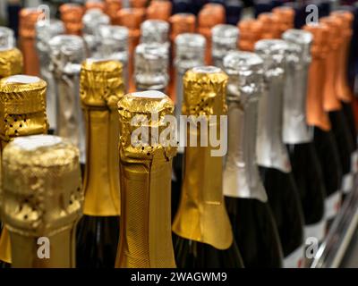 Die Partie Sekt oder Champagnerflaschen stehen in einer Reihe auf dem Weinregal. Selektiver Fokus. Stockfoto