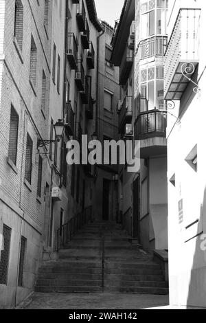 Vertikale schwarz-weiße Aufnahme von Treppen zwischen zwei Häusern in Toledo, Spanien Stockfoto